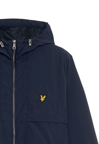 Marineblå hættejakke med struktureret overflade, der har en frontlynlås, mesh-foring og et gult broderet logo på brystet.