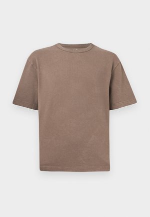 Paprastas rudas trumpomis rankovėmis medvilnės marškinėlis su apvalia iškirpte ir laisvu kirpimu, eksponuojamas prieš šviesiai pilką foną.