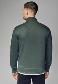 Dunkelgrüner Sweatshirt mit hohem Kragen, langen Ärmeln, gerippten Bündchen und glatter Textur, mit einer dezenten Nahtdetails auf der Rückseite.