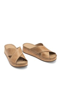 Skórzane klapki na koturnie w kolorze brązowym z krzyżującymi się paskami, zaokrąglonym otwartym noskiem i teksturowaną drewnianą podeszwą. Szwy wzdłuż krawędzi.