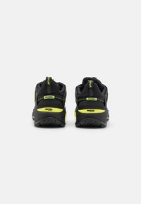 Scarpe da escursionismo nere con materiale testurizzato, accenti in giallo neon, suola con tasselli e linguette di trazione contrassegnate con "ESPLORA" e "STAGIONI".