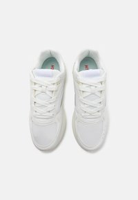 White athletic shoes with mesh and synthetic upper, lace-up design, padded tongue, and red accent on the insole. Smooth rubber sole.
