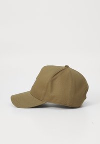 Casquette de baseball couleur khaki avec une visière courbée, une forme structurée, une texture en tissu et une petite étiquette blanche sur le panneau avant.