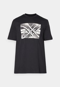 Must mustre tee-shirt musta lühikeste varrukatega, mille keskosas on valge graafika, mis kujutab ristuvaid jooni ja mustreid.