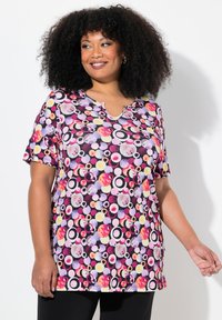 Top de manga corta con un vibrante patrón de lunares multicolores sobre fondo negro, con escote en forma de U y tejido suave.