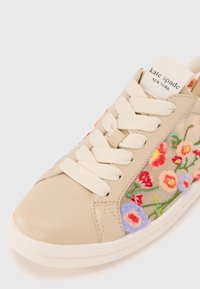 Beige lær sneaks med kremfargede snørebånd, med fargerik blomsterbroderi på sidene og en hvit gummisåle.