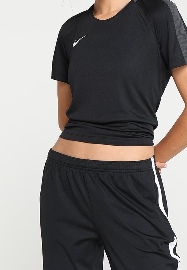 Czarna sportowa koszulka z krótkimi rękawami i zaokrąglonym dekoltem, zestawiona z czarnymi spodniami dresowymi z białymi paskami po bokach i elastycznym pasem.