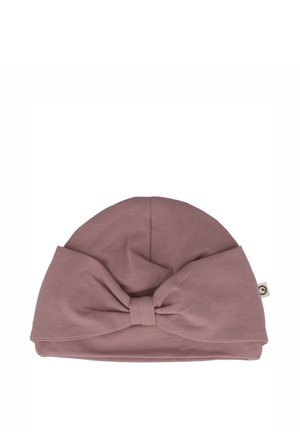 Cappello di cotone morbido e rosa con una parte superiore arrotondata e un grande fiocco decorativo frontale. Presenta un'etichetta sul lato. Texture liscia.