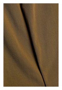 Gros plan d'un tissu brun lisse avec un pli diagonal créant des ombres et des variations de texture à la surface.