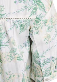 Tissu blanc avec de fines rayures verticales et un imprimé floral vert, jaune et violet clair, avec un détail décoratif de couture ajourée.