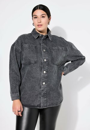Schwarzes Denim-Shirt mit durchgehender Knopfleiste, zwei Brusttaschen, lockerer Passform und langen Ärmeln. Glatte Textur mit minimaler Abnutzung.