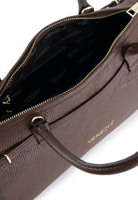 Brown leather handbag with a textured surface, zip closure, and gold-tone hardware. Interior features dark lining with logo pattern.