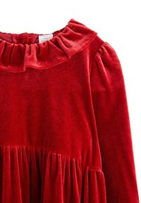 Czerwona sukienka z aksamitu z falbaniastego dekoltu, bufkami i marszczeniami na spódnicy, które dodają tekstury i wymiaru.