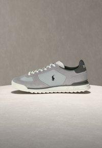 Sivo-beli nizki športni copati z belimi vezalkami, črnim notranjim podlogom in logotipom Polo na boku in peti.