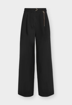 Pantalon noir taille haute à jambes larges avec plis, ceinture assortie avec boucle dorée et accessoire chaîne dorée sur le côté droit.