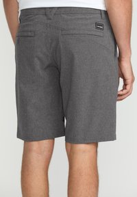 Gray shorts made of textured fabric, featuring a rear pocket and branding label. The design includes flat seams and knee-length cut.