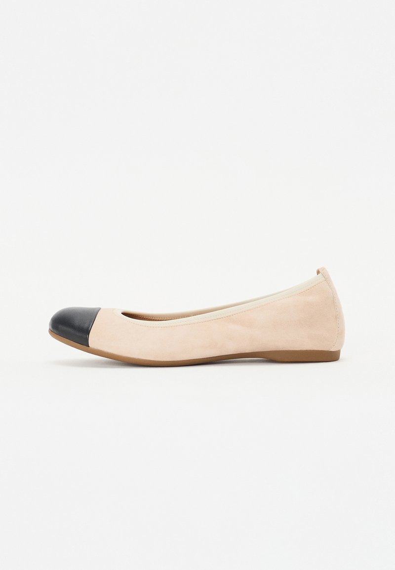 Chaussure plate en daim beige avec un bout rond noir et une semelle basse marron, vue de côté sur fond blanc.