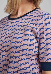 Pletený svetr z jemného růžového materiálu se vzorem modrého běžícího psa. Má kulatý námořnický výstřih a krátké rukávy s námořnickými manžetami.