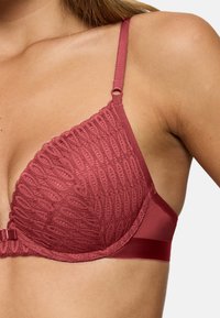 Červená krajková a saténová podprsenka s tvarovanými košíčky, která má strukturovaný vzor, nastavitelná ramínka a saténový pás pro zvýšené pohodlí.
