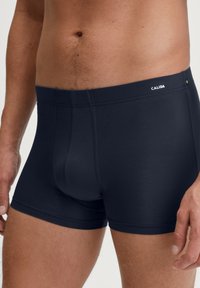 Navy blue boxer briefs made from a soft, stretchy fabric, featuring a seamless waistband with a small logo detail.