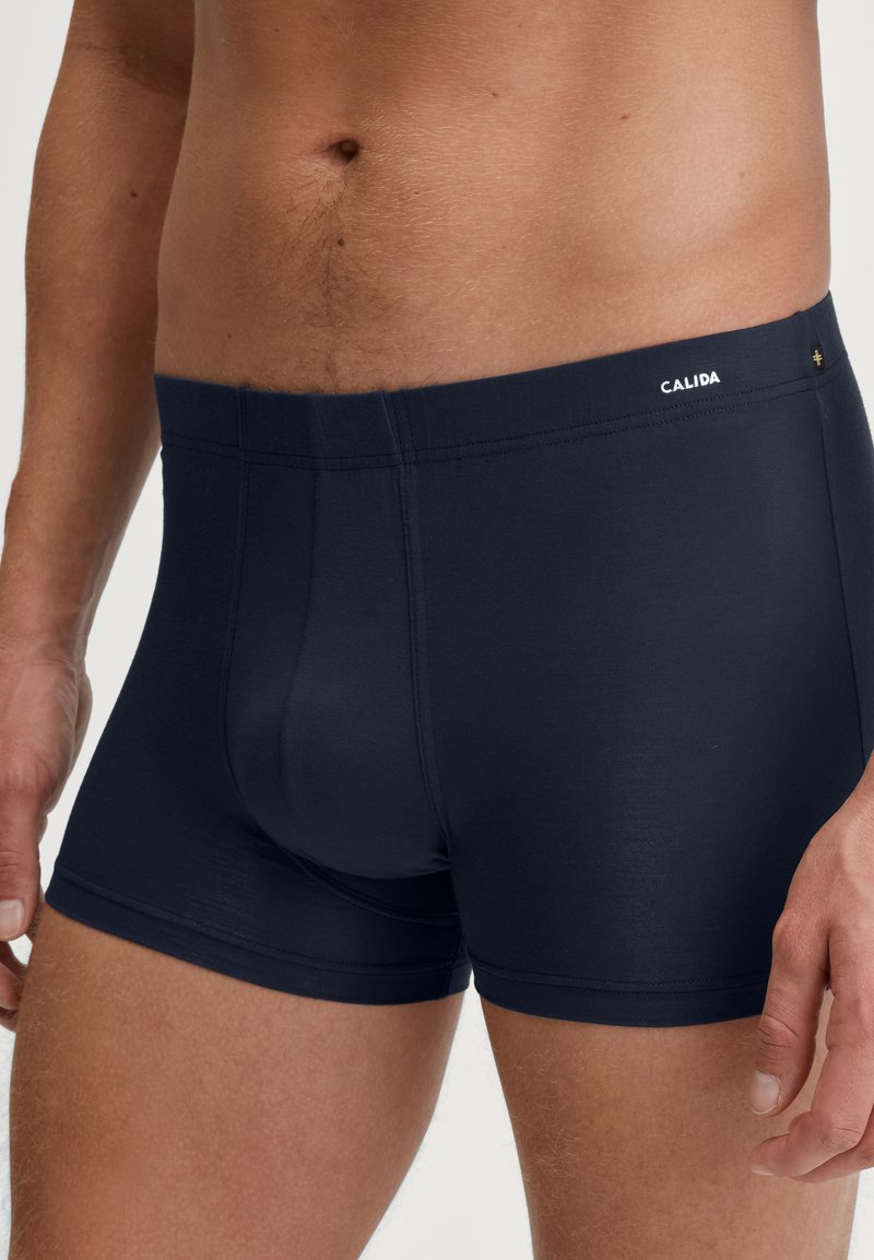 Navy blue boxer briefs made from a soft, stretchy fabric, featuring a seamless waistband with a small logo detail.