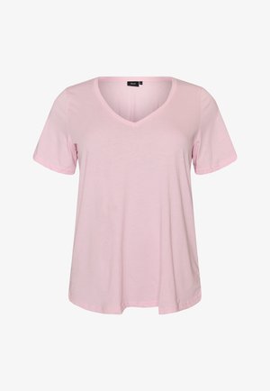 Jasnoróżowa koszulka z krótkim rękawem, dekoltem w serek i luźnym krojem, z małą czarną metką przy kołnierzu.