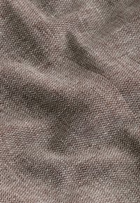 Braun und weißer, strukturierter Stoff mit geometrischem Muster, der ein gewebtes Aussehen und eine sanfte Drapierung aufweist und eine glatte Textur zeigt.