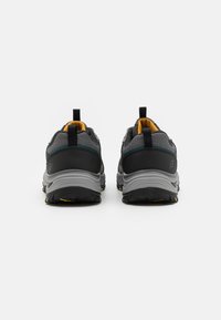 Černé a šedé sportovní boty s síťovanými panely, gumovými podrážkami a žlutými akcenty. Disponují poutkem na patě pro snadné obouvání.