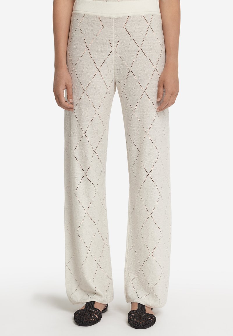 Ljust beige vida byxor med ett öppet stickat diamants mönster, som har en bekväm midja och en strukturerad tyg.