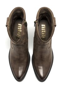 Botas de tobillo de cuero marrón con punta afilada, un acabado suave, costuras decorativas y cremalleras laterales para facilitar el uso.