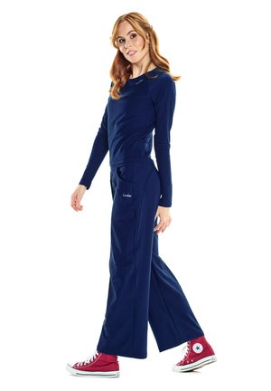 Marineblaue Langarmoberteil kombiniert mit weit geschnittenen marineblauen Hosen. Die Schuhe sind rote High-Top-Sneaker. Einfaches Design mit minimalen Akzenten.