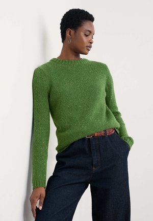 Groene gebreide trui met een ronde hals, een gestructureerd steekpatroon en lange mouwen, gecombineerd met donkere denim broek en een geweven riem.