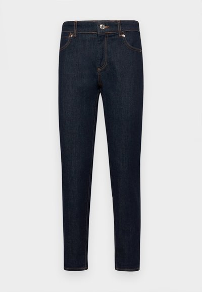 Σκουρόχρωμες τζιν παντελόνες με στενή εφαρμογή, σχέδιο πέντε τσεπών και αντίθετες πορτοκαλί ραφές. Διαθέτουν μεταλλικό κλείσιμο στη μέση.