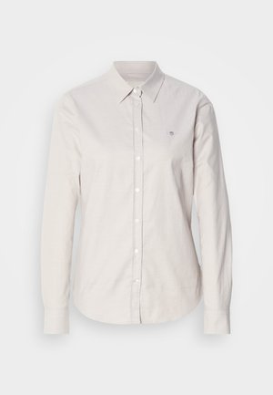 Light beige button-up shirt made of cotton with long sleeves, a classic collar, and subtle embroidered logo on the left chest.