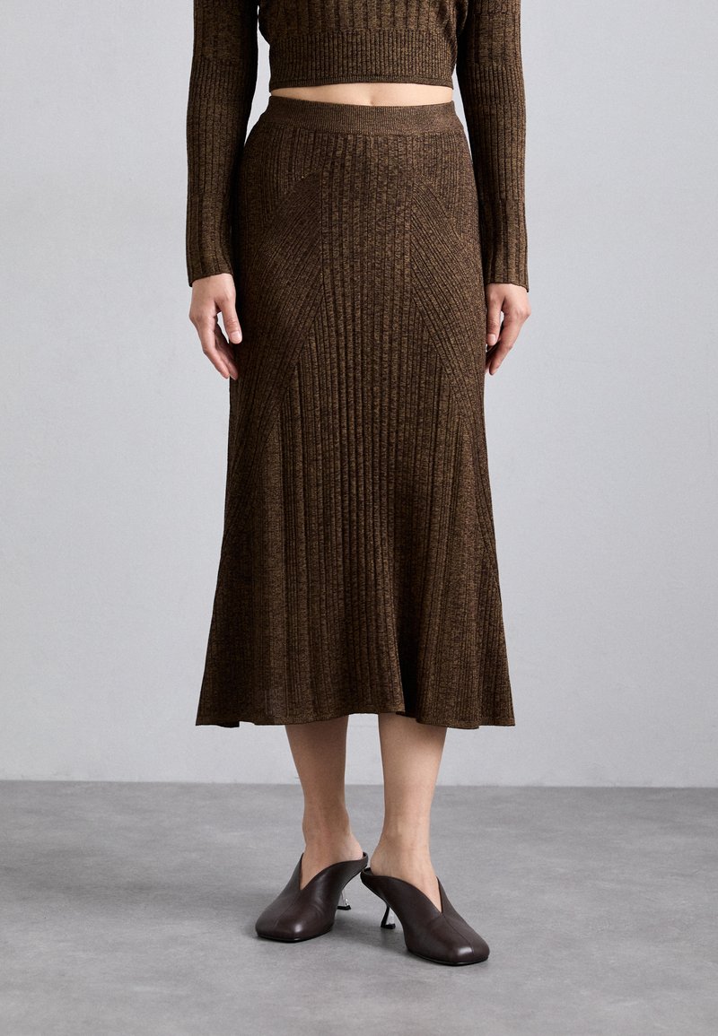 Ribbed, brown knit midi skirt with a flared hem and stretch fabric, paired with heeled brown mules showcasing an open design.