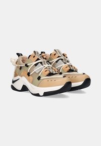 Zapatillas deportivas beige y verdes con parte superior de malla, acentos negros, mediasuela blanca y suela exterior de goma texturizada. Presenta un sistema de cordones prominente.