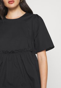 Schwarzes Kurzarmoberteil mit rundem Ausschnitt, das eine elastische Taille mit Rüschendetails und einem weichen, leichten Stoff aufweist.