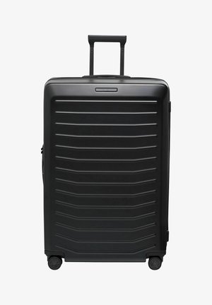 Valise rigide noire avec une surface texturée présentant des rainures horizontales, une poignée télescopique et quatre roues pour la mobilité.
