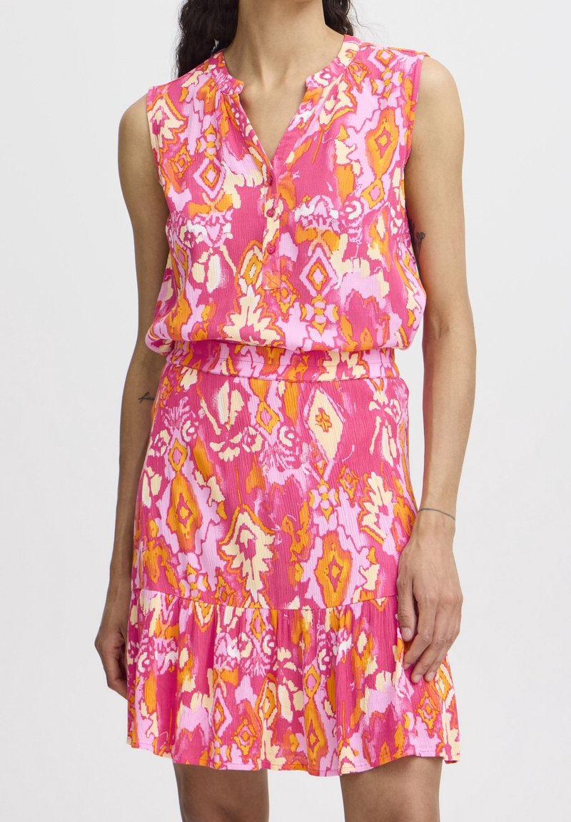 Robe sans manches avec un motif floral abstrait rose vif, orange et blanc, encolure en V, taille cintrée et jupe à volants.