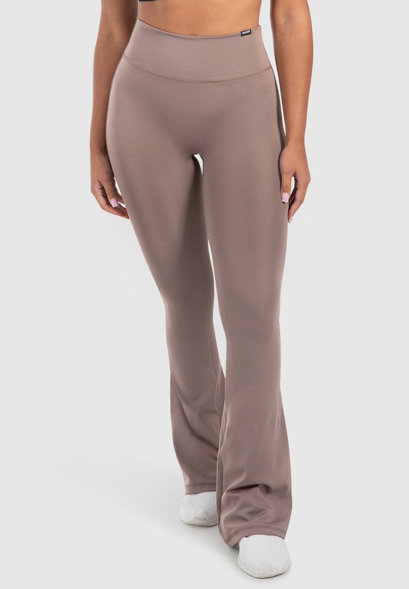 Uitgebreide leggings van zacht beige stof met een hoge tailleband. Zijdezachte textuur en minimale naden, gecombineerd met witte sportschoenen.