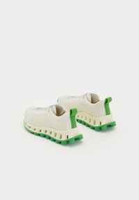 Biele sneakers na šnurovanie so zelenými akcentmi, s textilným pleteným zvrškom a robustnou zelenou podrážkou so silným valcovým tvarom.