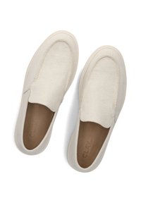 Een paar beige instapcanvas schoenen met ronde neuzen en tan binnenzolen waarop het woord "CLAY" is gedrukt, weergegeven vanuit bovenaanzicht.