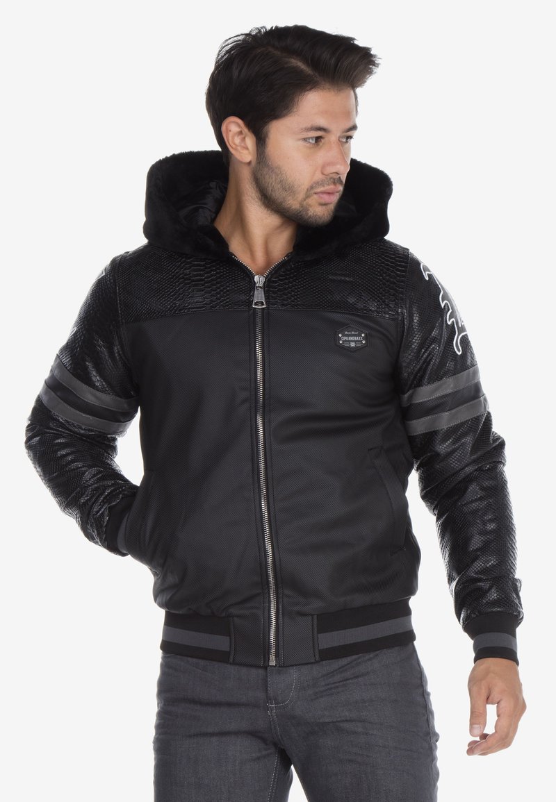 Black bomber jacket with faux fur hood, textured panel accents, two horizontal stripes on sleeves, and zip closure. Features a slim fit design.