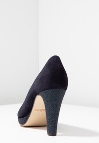 Marinblå mocka högklackad sko med en glittrande blå plattform och klack, med spetsig tå och en slät yta.