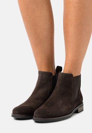 Bottes chelsea en daim marron avec panneaux latéraux élastiques, bout arrondi et petit talon empilé. Tige texturée avec une légère brillance.