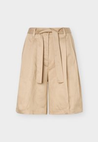 Beige højtaljede shorts med bæltestropper, stofbælte og vide ben, vist mod en ensfarvet baggrund.