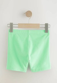 Muntgroene katoenen shorts tentoongesteld op een houten en metalen hanger. Heeft een zachte textuur en een eenvoudig ontwerp zonder zichtbare patronen.