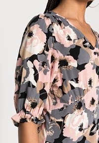 Květinová blůza z lehkého materiálu, s jemně růžovými a tlumeně šedými květy na černém pozadí, s nabíranými rukávy a výstřihem do V.