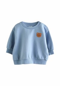 Vaaleansininen collegepaita, jossa on pyöreä kaula-aukko, lyhyet puffihihat ja ribbireunat. Edessä on pieni ruskea karhupatch.
