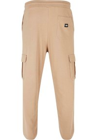 Beige cargobyxor av mjukt tyg, med elastisk midja, två sidofickor och en bakficka med etikett.